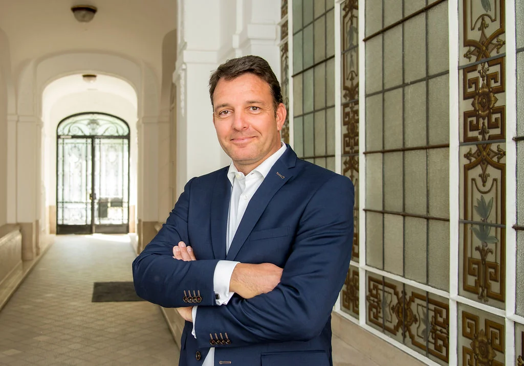 Filip Coolen in a professional portrait, standing in a historic corridor